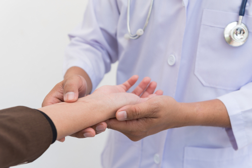 An orthopedic doctor examines the wrist of a patient to help evaluate carpal tunnel syndrome. 