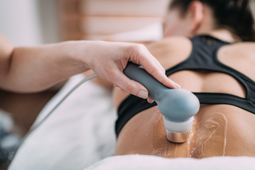 An orthopedic doctor utilizes ultrasound-guided local anesthetic injections to help relieve the back pain of a female patient.