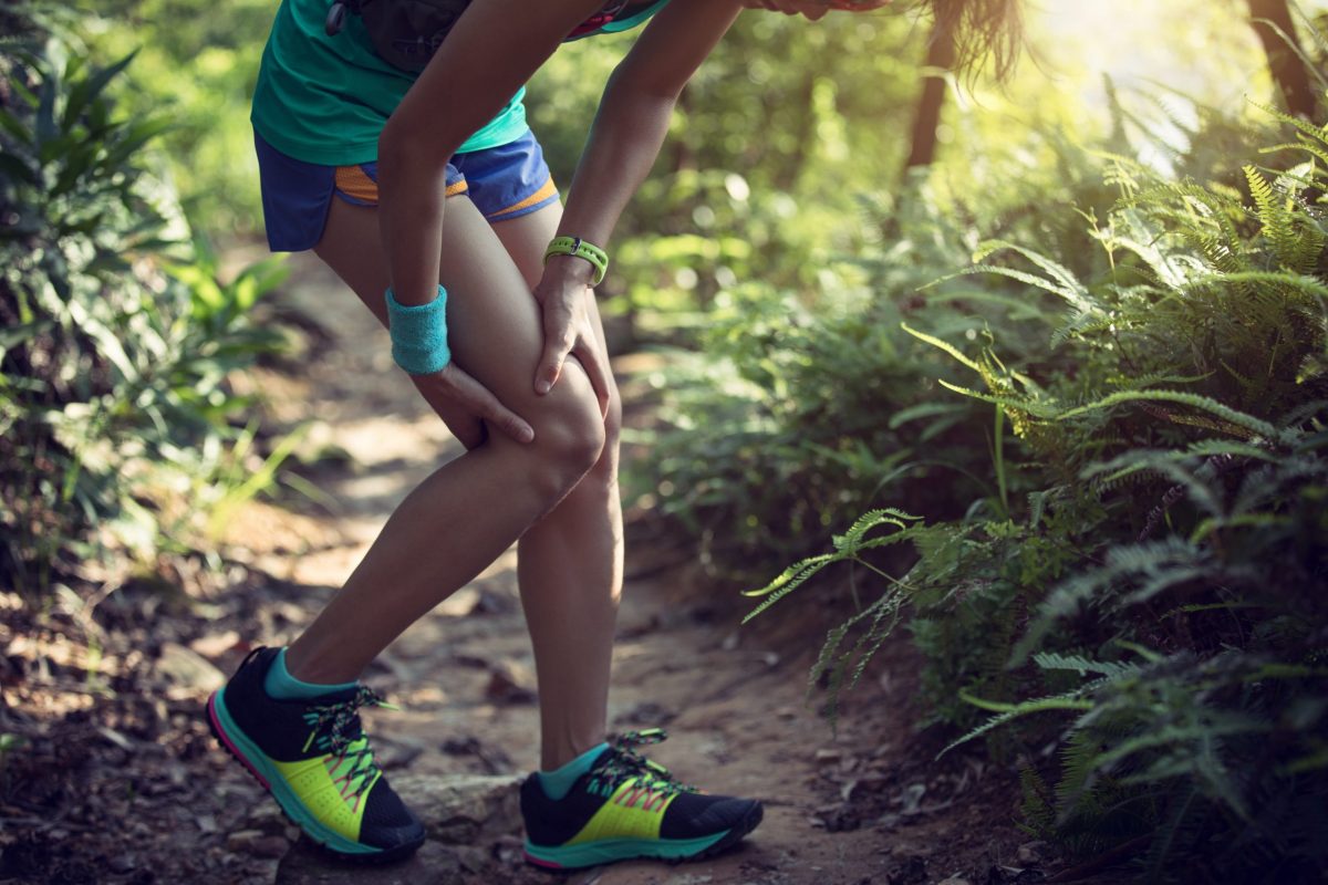  Female trail runner holds her leg that has just sustained a knee injury. 