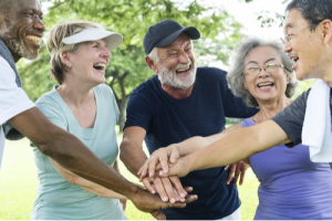 A group of happy, healthy seniors huddle after exercising to celebrate.