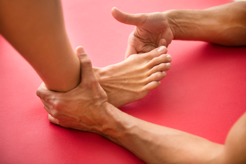 A male orthopedic foot and ankle doctor assesses a patient’s foot with hallux rigidus for possible big toe replacement.