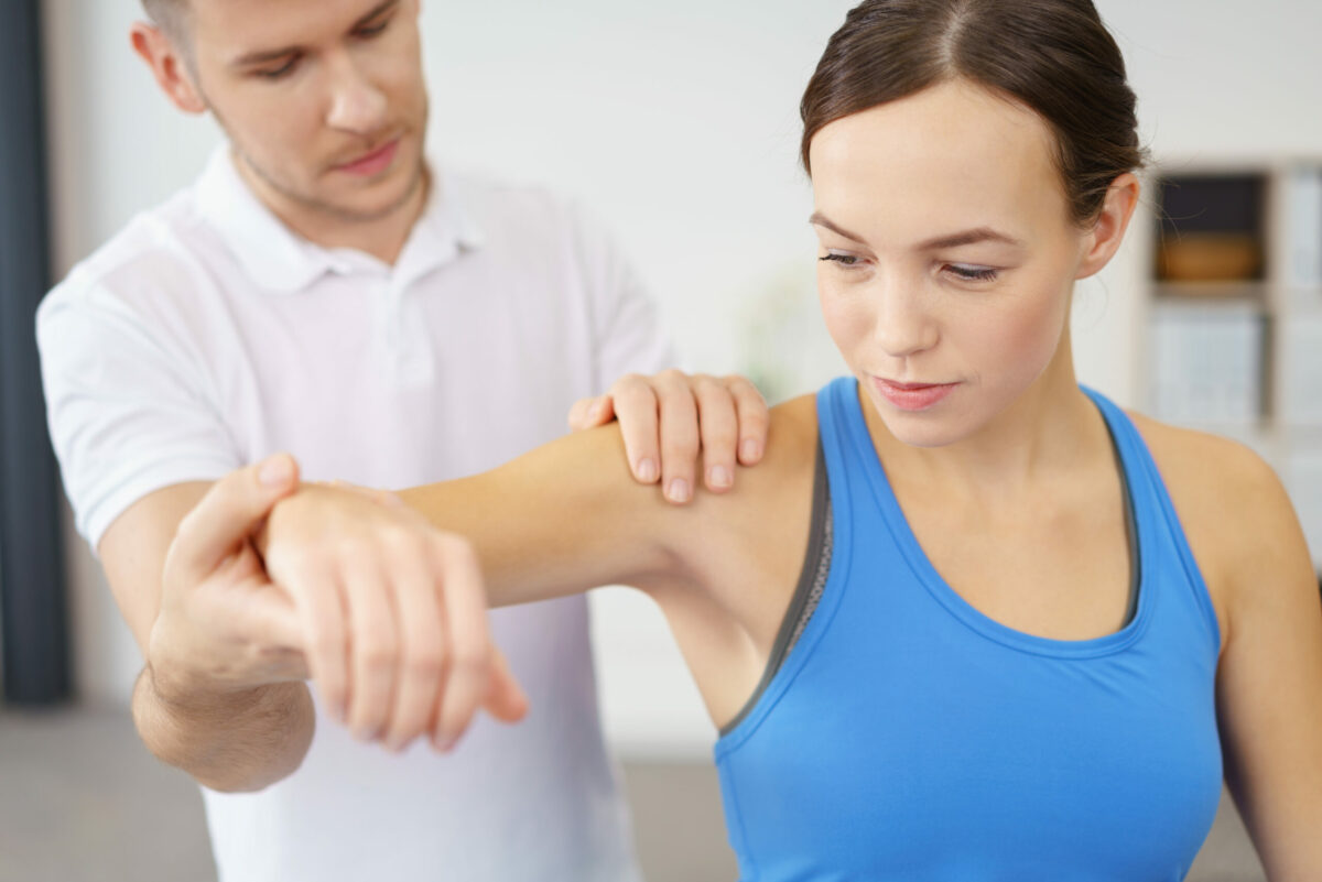 A physical therapist works with a patient on her shoulder. 