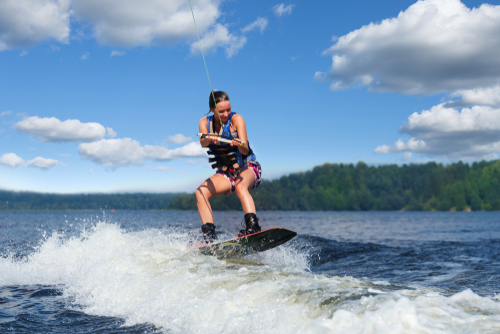 Young woman in life jacket wakeboarding in the ocean. 