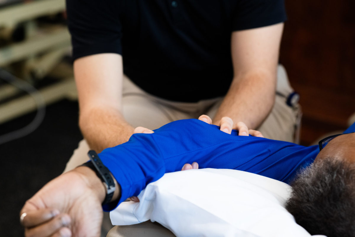 A physical therapist works on the elbow of a person lying down