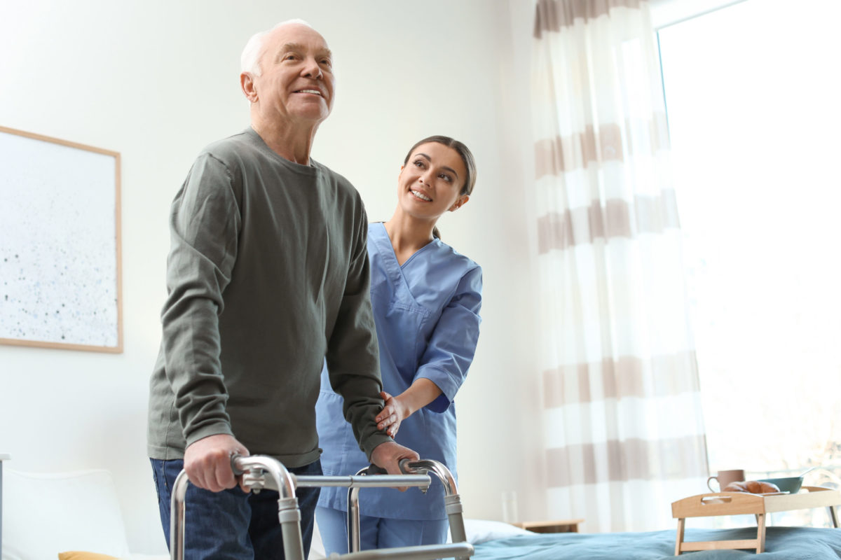  A female orthopedic specialist helps an active mature man with his walker after anterior hip replacement surgery.