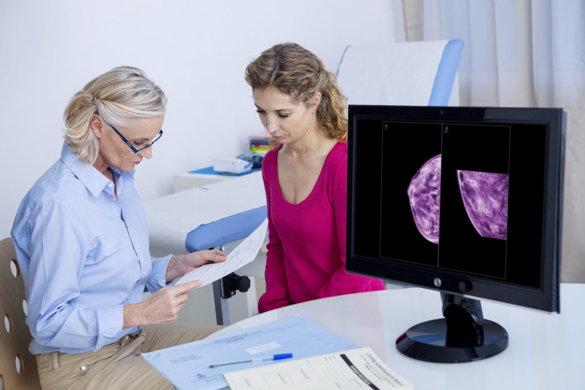 A female patient consults with a doctor about breast cancer treatment with images on a computer screen. 