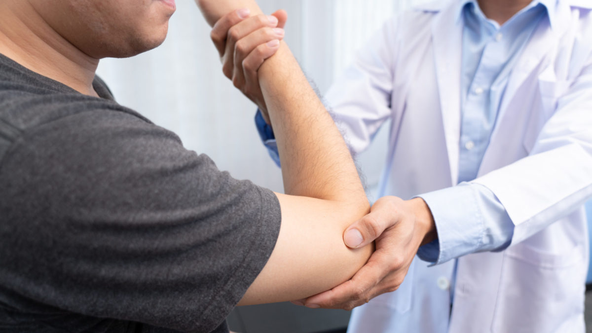 An orthopedic doctor examines a man’s elbow to find the source of a popping or clicking sound. 