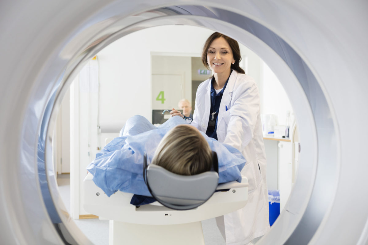 Orthopedic doctor guiding patient through MRI machine.