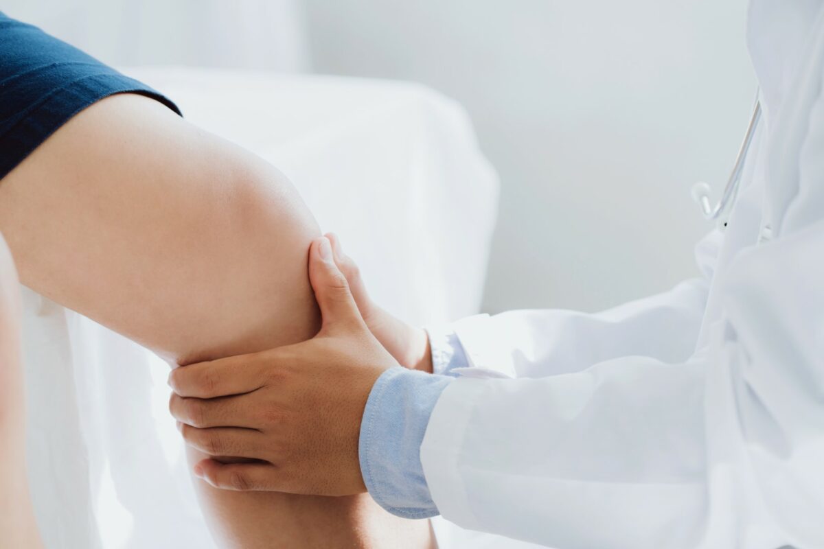 A knee doctor is examining and treating a patient’s injury in an orthopedic clinic.