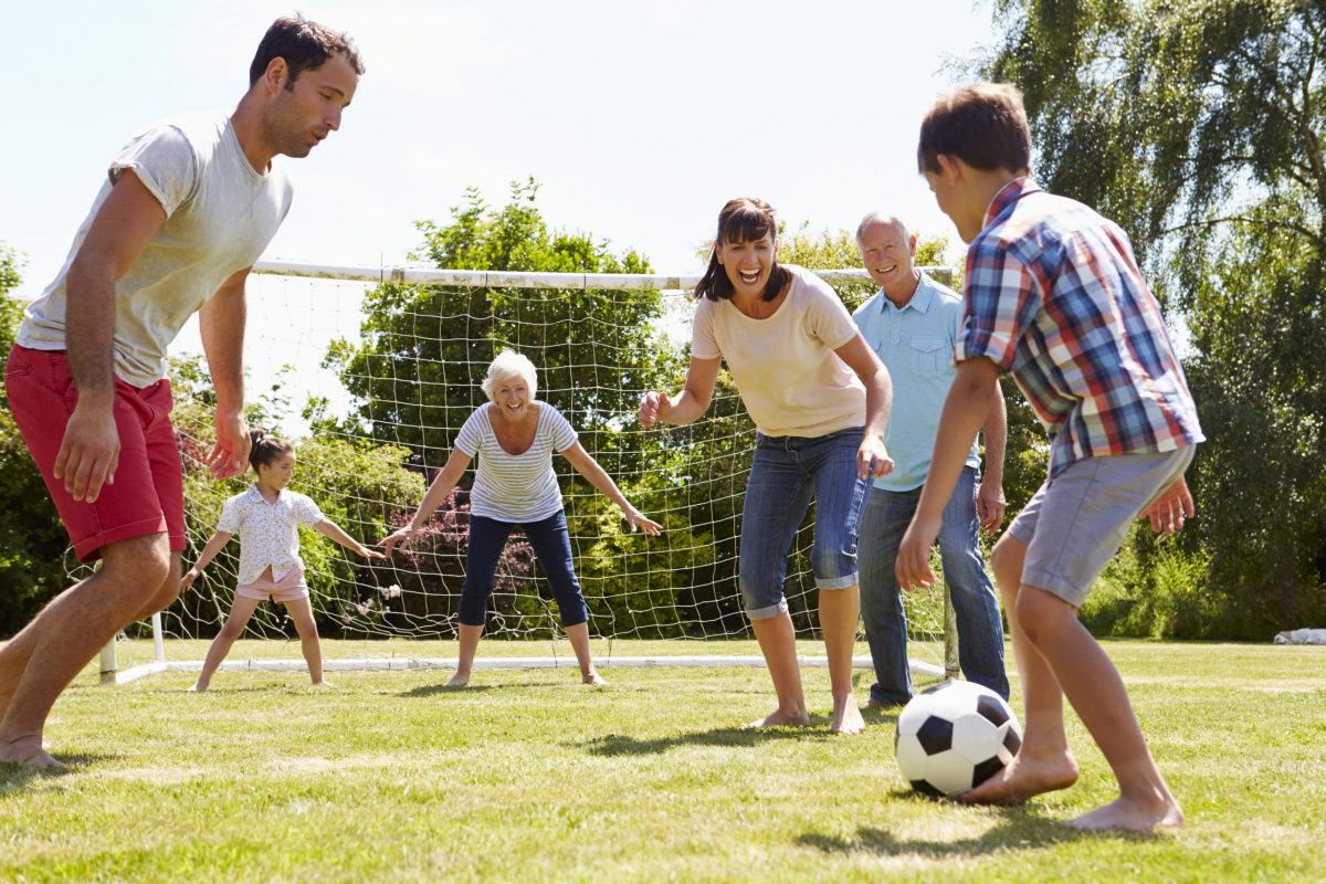  Multigenerational family plays soccer in the backyard. 