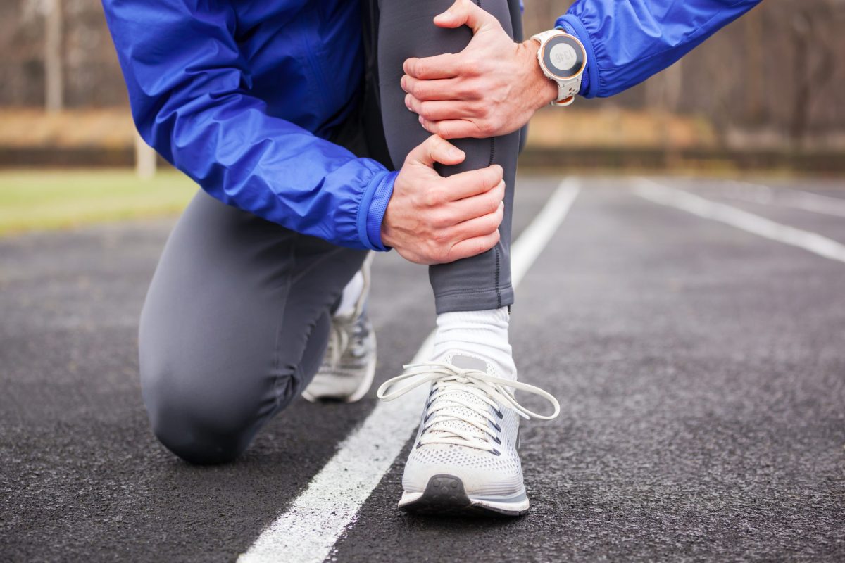  Runner holds shin in pain while working out on a track. 