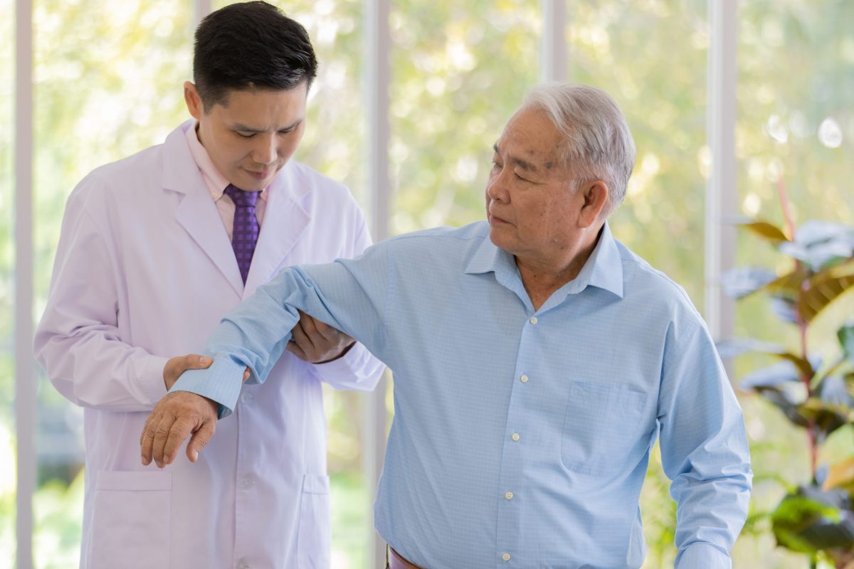 A doctor examines the elbow of a patient experiencing joint pain. 