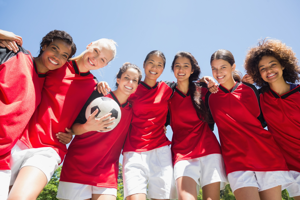 A soccer team in red jerseys huddles together.
