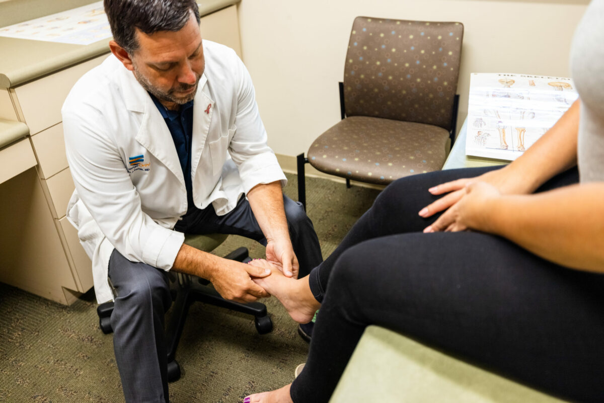  A male foot and ankle doctor examines the foot of a male patient after foot and ankle surgery. 