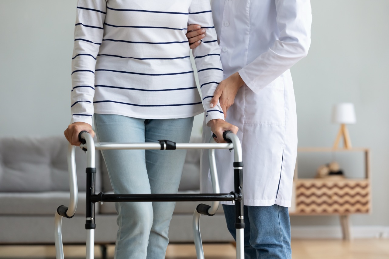 A caregiver helping a senior woman using a walker.